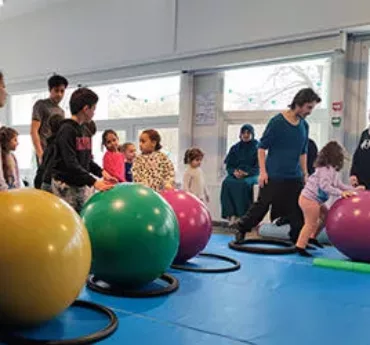 Enfants au centre social Andrée Chedid avec des gros ballons de gym et des cerceaux de toutes les couleurs